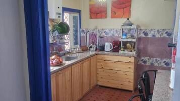 A kitchen with wooden cabinets, a tiled floor, and a dining area with chairs.