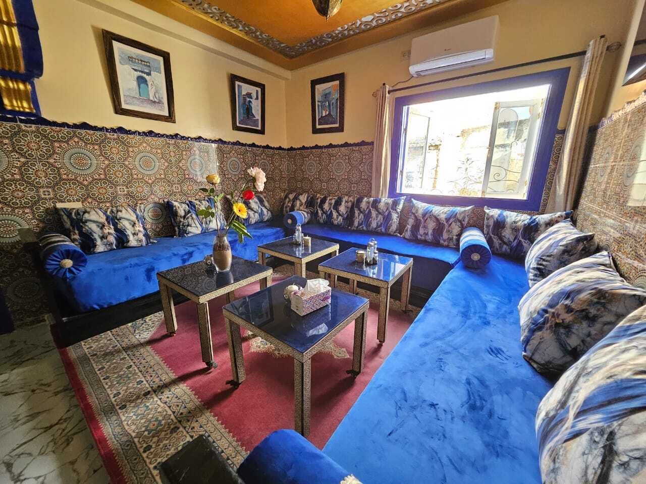 Una sala de estar con un conjunto de sofá, dos mesas auxiliares y un papel tapiz estampado.