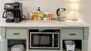 Une cuisine équipée d’une machine à café, d’un four à micro-ondes et d’étagères de rangement.