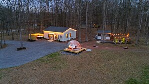 Une maison avec un jacuzzi, une structure en forme de dôme et un petit abri équipé de lumières.