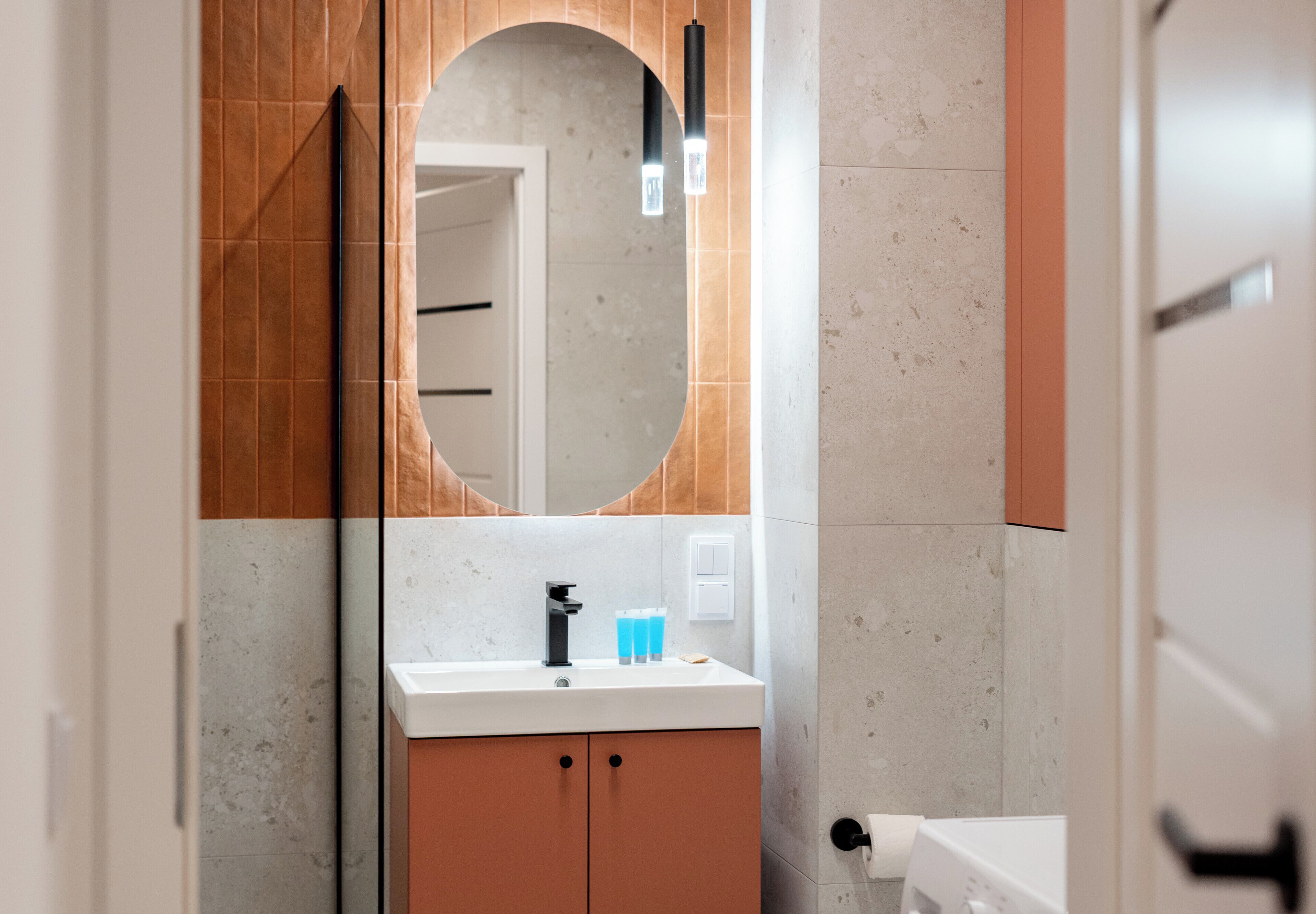 A bathroom with a round mirror, a sink, and a towel rack.