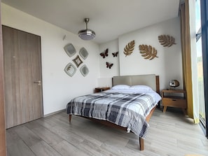 A bedroom with a bed, a ceiling fan, decorative wall art, and a wooden door.
