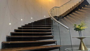 Una moderna scala con gradini in legno e ringhiere in vetro, che conduce a un piano superiore.