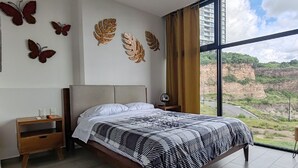 Una camera da letto con un letto, un comodino, una lampada a parete e un'ampia finestra vista scogliera.