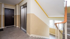 A hallway with a door, an elevator, and a staircase with a handrail. - Las Bielański Homely Apartment (Warszawa)