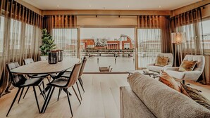 Ruime woonkamer met een eettafel, stoelen, een bank en uitzicht op een gebouw aan de overkant van het water.