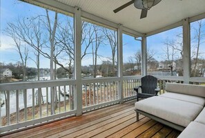 Eine überdachte Veranda mit Seeblick, ein Sessel und eine Couch.