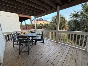 A wooden deck with a table and chairs, surrounded by a white railing, overlooking a residential area with palm trees. - Whale Hello There . Gulf Coast Retreat . Walk to Beach . 2 Bed Duplex (Gulf Shores)