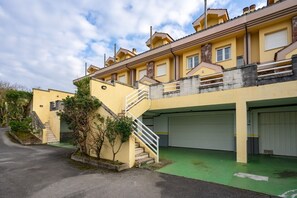 Un edificio de varios pisos con fachada amarilla, una escalera y un estacionamiento verde.