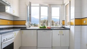 Una cucina con fornello, forno e lavastoviglie, con una finestra che offre vista sull'esterno.