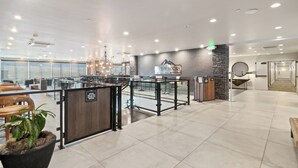 Een ruime lobby met een receptiebalie, een zithoek en een bordje voor 'On the Rocks Bar'.
