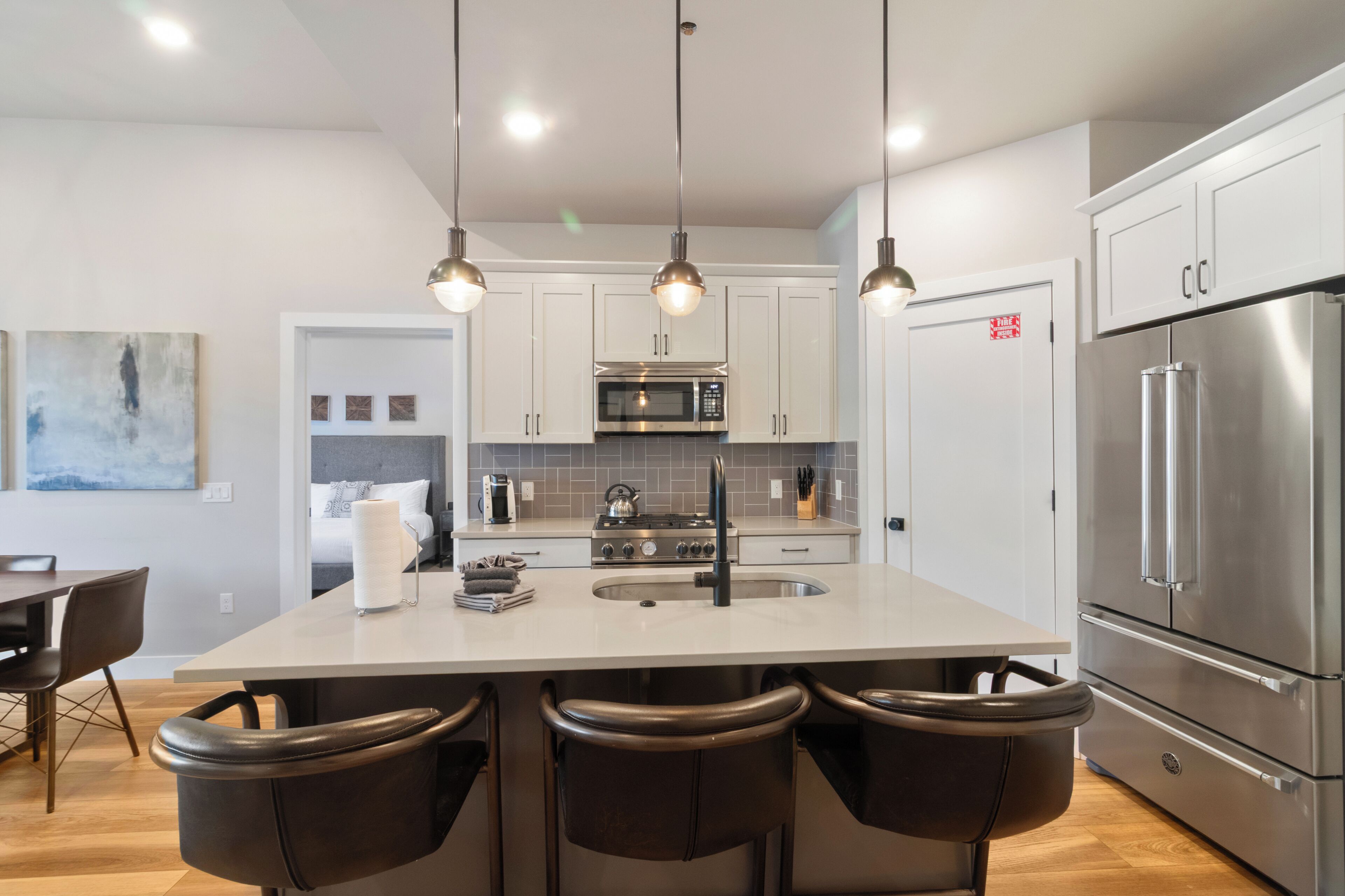 A modern kitchen with a central island, stainless steel appliances, and pendant lighting.