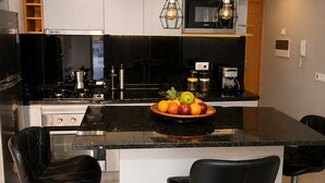 A modern kitchen with a central island, bar stools, and pendant lighting. - Apartment Achada St Antonio Rua Principal AC, WIFI (Praia)