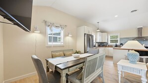 Une cuisine moderne dotée d’un réfrigérateur encastré, d’une table à manger avec des chaises et d’un petit îlot central agrémenté d’une lampe.