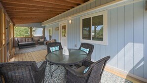 Une terrasse couverte avec une table ronde et des chaises en osier, un canapé et une fenêtre.