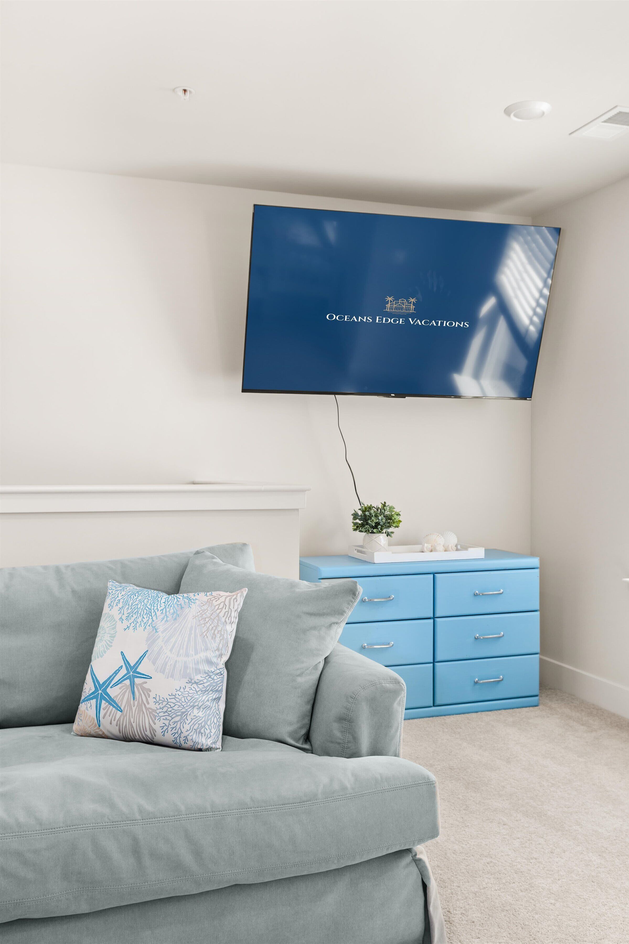 Una sala de estar moderna con un sofá gris, un aparador azul y un televisor de pantalla plana montado en la pared.