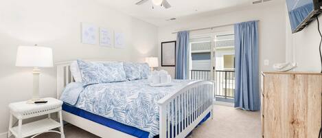 A bedroom with a bed, a nightstand, a wooden cabinet, a ceiling fan, and a window with curtains.