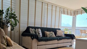 Una sala moderna con un sofá, una mesa de centro, una planta en maceta y vistas al exterior.