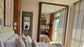 Un dormitorio moderno con una cama grande, una mesita de noche con lámpara, una alfombra estampada y vistas al exterior.