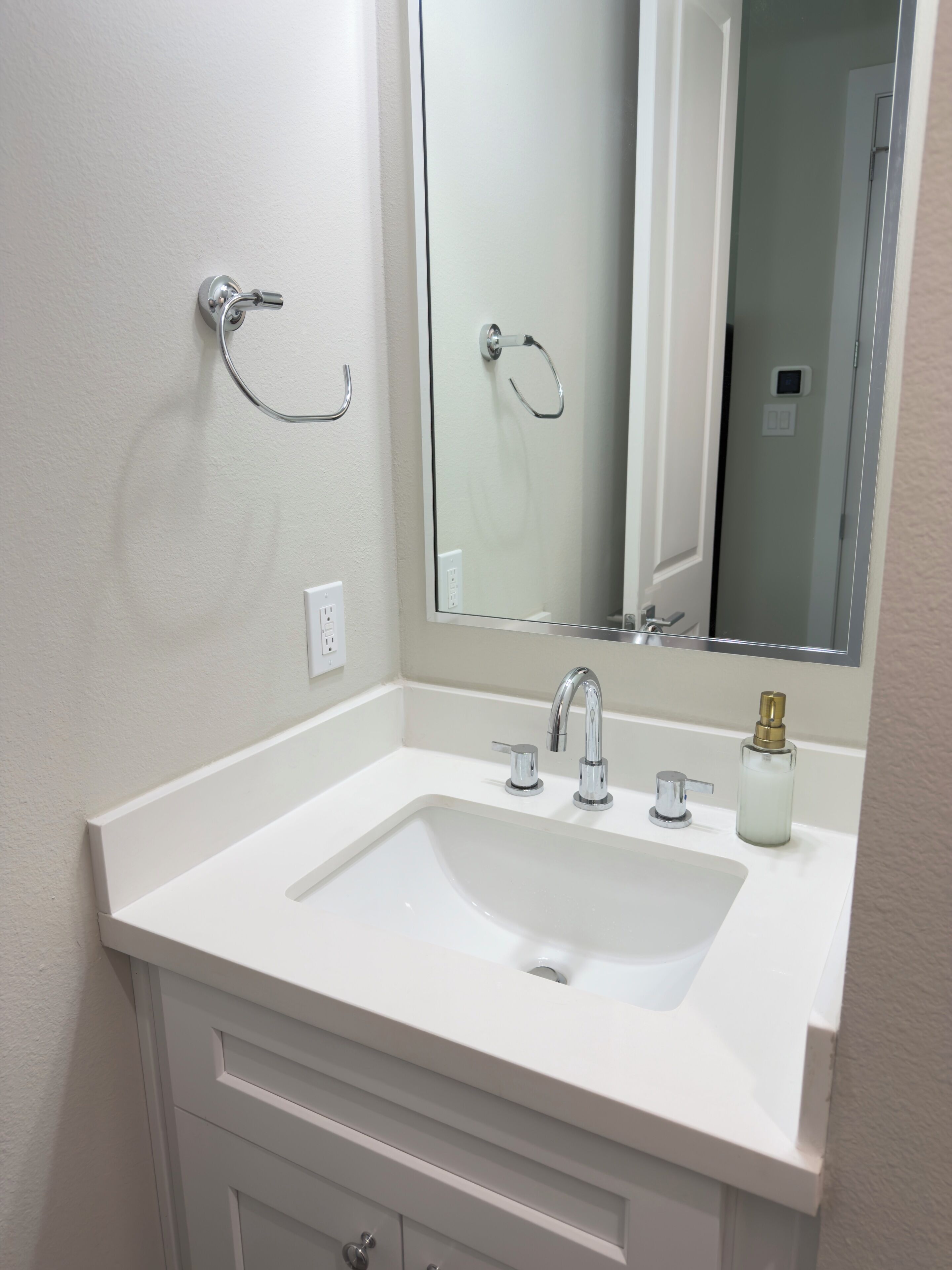 A bathroom with a white sink, chrome faucet, and a mirror above it.