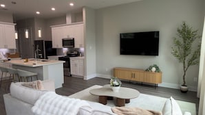 Uma sala de estar moderna com um sofá, uma mesa de centro e uma TV fixada na parede.