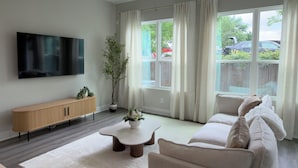 Uma sala de estar moderna com sofá, mesa de centro, TV e um vaso de planta.