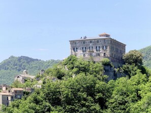 A historic building with multiple stories, situated on a hillside with lush greenery. - Lovely apartment for 4 people with A/C, WIFI, terrace and panoramic view (Toirano)