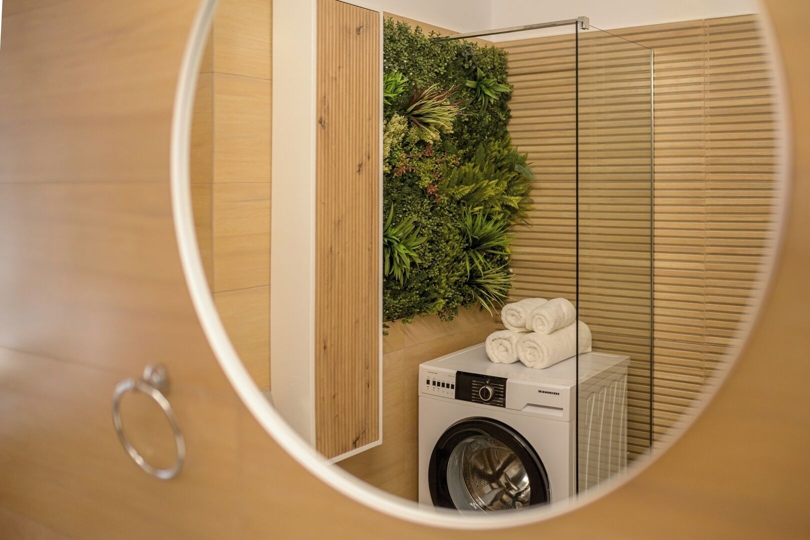 Un espace buanderie équipé d’un lave-linge, de serviettes et d’un jardin vertical.