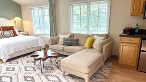 Ein Schlafzimmer mit einem Bett, einem Sofa, einem Couchtisch und einer Küchenzeile mit Schränken und einem Kühlschrank.