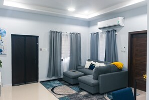 Un salon moderne avec un canapé gris, une table basse et un fauteuil bleu.