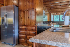 A kitchen with a stainless steel refrigerator, wooden cabinets, a granite countertop, and a dishwasher. - 5BR/5BA Cabin | Views, Hot Tub & Pool Table (sevierville)
