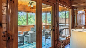 A wooden cabin with a porch area featuring wicker furniture and a view of the outdoors. - 5BR/5BA Cabin | Views, Hot Tub & Pool Table (sevierville)