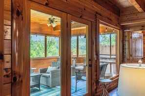 A wooden cabin with a porch area featuring wicker furniture and a view of the outdoors. - 5BR/5BA Cabin | Views, Hot Tub & Pool Table (sevierville)