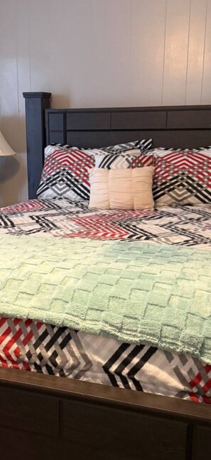 Un lit avec une couvre-lit à motifs, des oreillers et une courtepointe.
