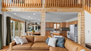 Un intérieur de chalet moderne comprenant un espace de vie, une cuisine et un balcon doté de rampes en bois.