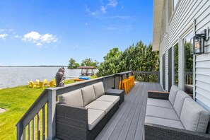 Una terraza con mobiliario exterior, vista al lago y un muelle con barcos.