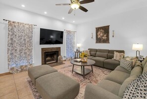 Un salon comprenant un ensemble de canapés, une cheminée, un téléviseur et un ventilateur de plafond.