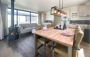 A modern kitchen with a dining area, a built-in stove, and a large window.