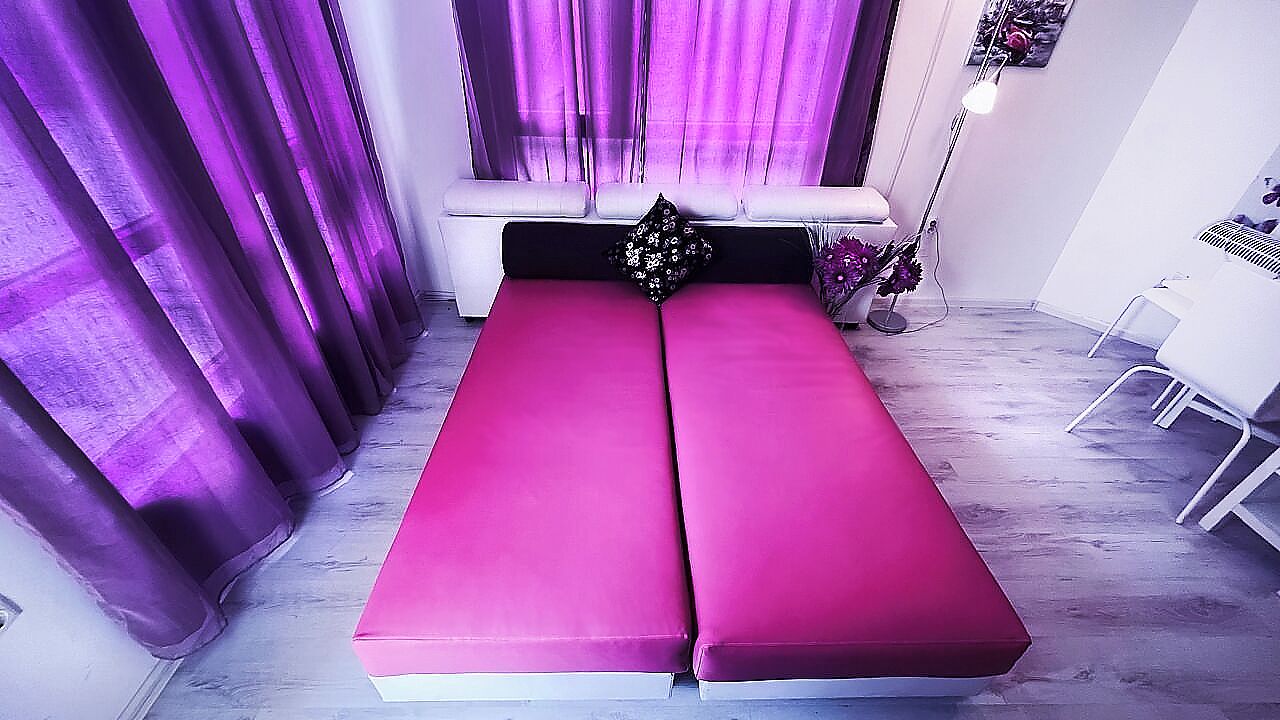A room with a bed, a bench, a floor lamp, and a chair.