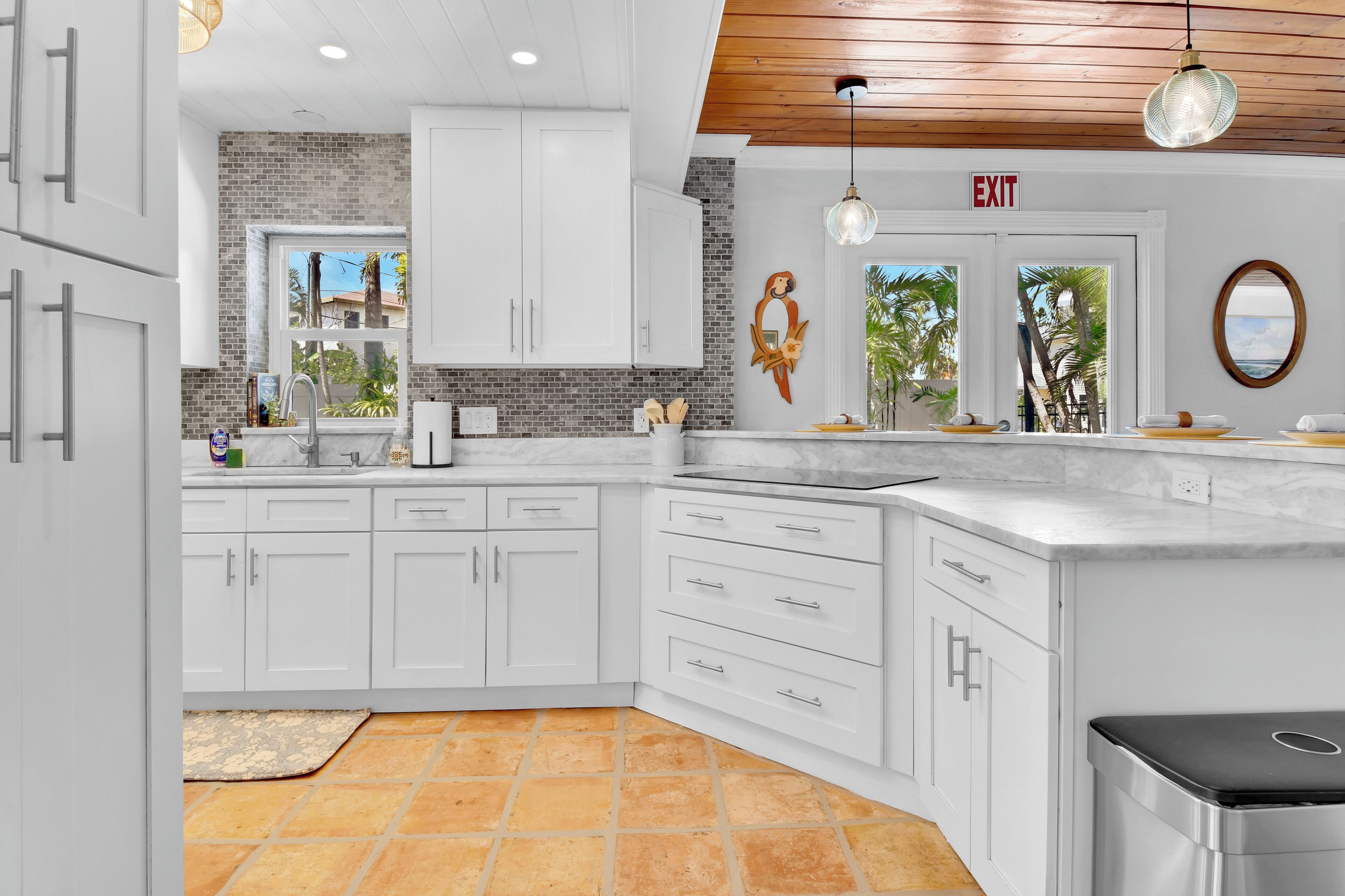 A modern kitchen with white cabinets, a brick backsplash, and a large island.
