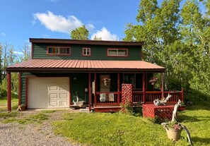 Ein zweistöckiges Haus mit rotem Dach, einer Veranda und einer Garage.
