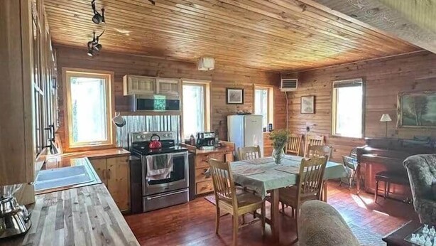 A cabin interior with a kitchen, dining area, and living room. - Two Houses, Twice the Fun (Glacier County)