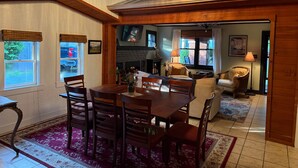 A dining area with a wooden table and chairs, a chandelier, and a view of the kitchen through an open archway. - The Bell Moon Cottage | Half a Block from Downtown (Black Mountain)