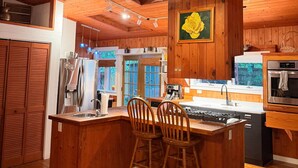 A wooden kitchen with a central island, built-in appliances, and a ceiling fan. - The Bell Moon Cottage | Half a Block from Downtown (Black Mountain)
