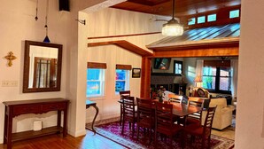 A dining area with a wooden table and chairs, a chandelier, and a fireplace. - The Bell Moon Cottage | Half a Block from Downtown (Black Mountain)