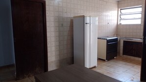 A kitchen with a refrigerator, stove, and a window with blinds.