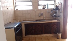 A compact kitchen with a stove, sink, and tiled backsplash.