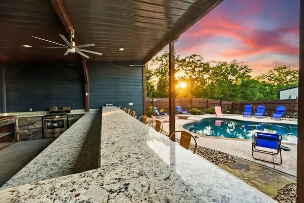 A modern kitchen with granite countertops, a built-in oven, and a ceiling fan.