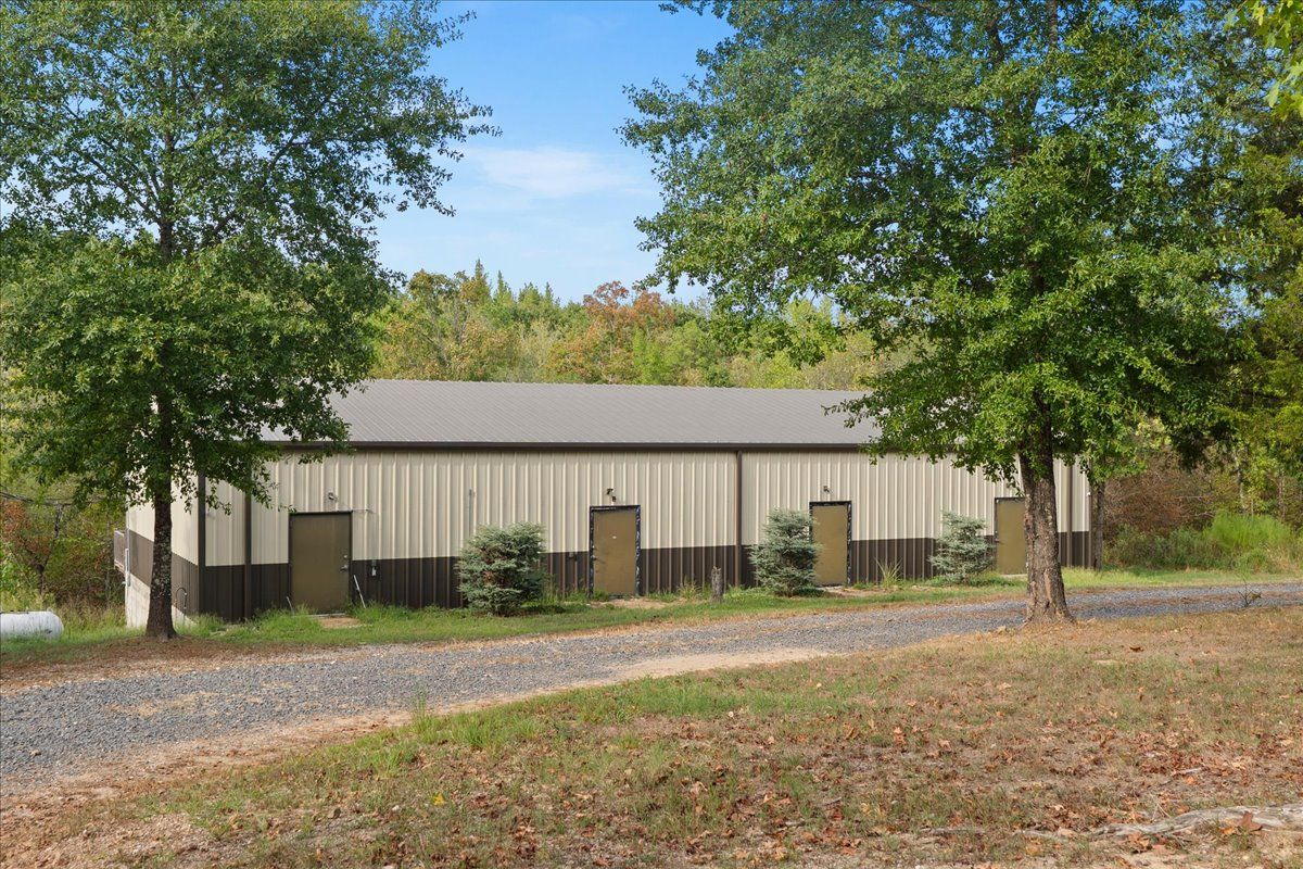 A large industrial building with a flat roof, multiple doors, and a gravel driveway.