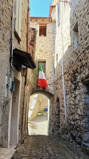 Un estrecho callejón empedrado con una bandera colgada de un edificio.